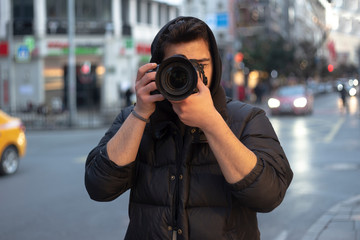 Young photographer taking photos on the streets of the city - obrazy, fototapety, plakaty