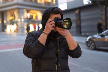Young photographer taking photos on the streets of the city - obrazy, fototapety, plakaty