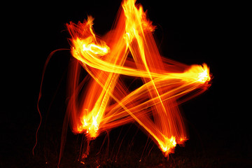 Orange fire star. Drawing of a star with fire on a black background. Texture of a fiery