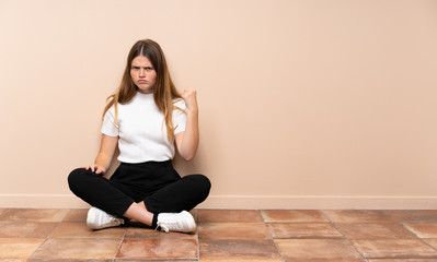 Ukrainian teenager girl sitting on the floor with angry gesture