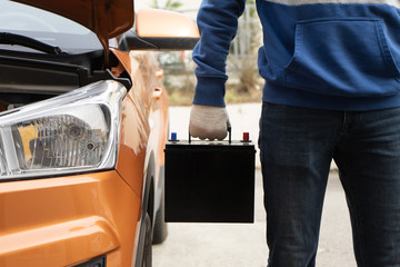 The buyer keeps the new black car battery next to the vehicle