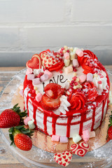 Top view of valentines day cake with strawberry, marshmallow and  heart shaped decorations on the kitchen table