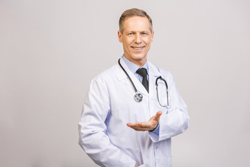 Doctor senior man, medical professional holding something in empty hand isolated over grey background.