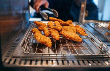 Chef's hand taking Crispy chicken nuggets  close-up in a restaurant