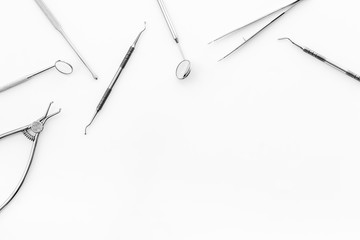 Stomatological tools on dentist's desk on white background top-down frame copy space
