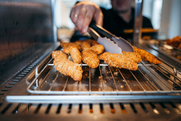 Chef's hand taking Crispy chicken nuggets close-up in a restaurant