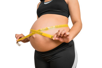 Pregnant woman using measuring tape to check baby development.