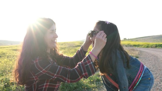 Mother trying on sunglasses to daughter
