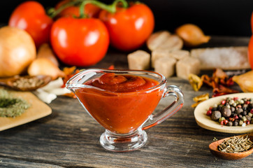 Closeup red tomato ketchup sauce with ingredients- vegetables and spices on a dark wooden background. Pasta sauce.
