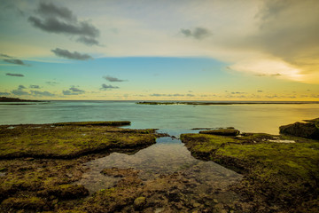 Seascape. Beach with rocks and stones. Low tide. Sunset time. Slow shutter speed. Soft focus. Melasti beach, Bali, Indonesia