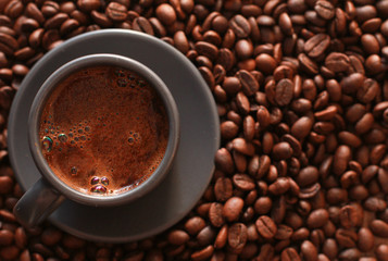 Grey cup of coffee and dark roasted beans. Closeup, copy space, top view. Coffee shop, espresso, fresh roast, drink  concept
