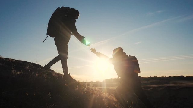 teamwork two men help helping hand business travel silhouette concept. two tourists lends lifestyle a helping hand climb the cliffs mountains. people climbers climb to the top teamwork overcoming