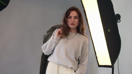 Young pretty woman model dressed in 90s style poses at a photo studio during a photo shoot.