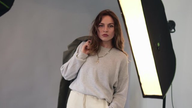 Young pretty woman model dressed in 90s style poses at a photo studio during a photo shoot.