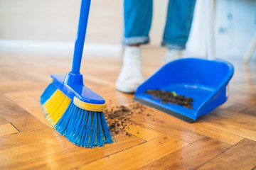 Latin man sweeping wooden floor with broom at home. - Powered by Adobe