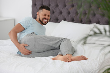 Man suffering from hemorrhoid on bed at home