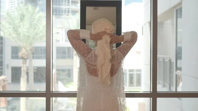 Young woman tying a turban before doing yoga. Slow motion, close-up.