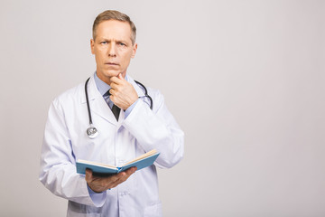 Senior doctor reading a book isolated over grey background.