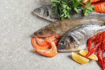Fresh raw fish and different seafood on light grey table