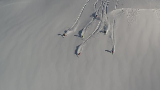 Aerial slow motion: five skiers and one snowboarder ride the first freeride line. off-piste skiing, Heli skiing. freeriders roll out large untouched snow valleys. Freeride ski & Epic free ride scene