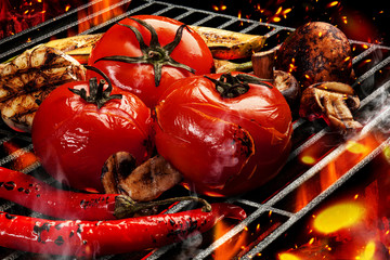 Barbecue bbq grilled tomatoes, zucchini, chili, champignons, halves of garlic. Flaming fire, ember charcoal and smoke. Cooking concept. Close up
