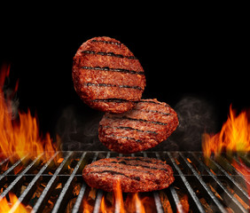 Falling down beef cutlets for burgers. Meat roasted on metal barbecue BBQ grill with flaming fire...