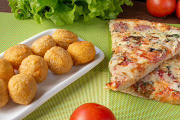 Pizza assorted slices with nuggets on a green napkin. Still-life. Wooden table. Greens and vegetables.