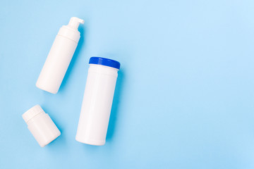 Group of plastic bottles on a blue background. Cosmetic products for design. Set of white cosmetic containers, top view with copy space.