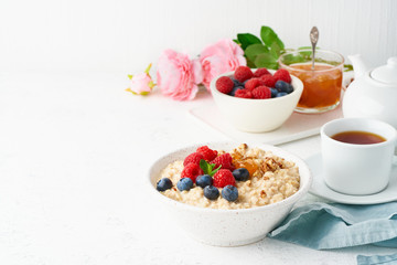 Oatmeal porridge with blueberry, raspberries, jam and nuts, side view, copy space,