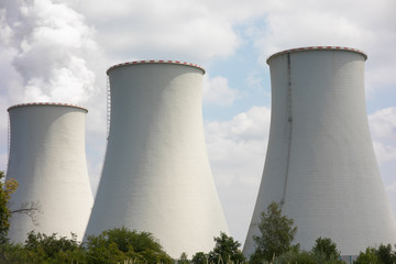 Fototapeta premium Nuclear power plant with big blue clouds. Technology, energy. Nuclear power plant in the field, cooling tower with steam.