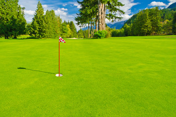 Obraz premium Golf place with gorgeous green and fantastic mountain and blue sky view