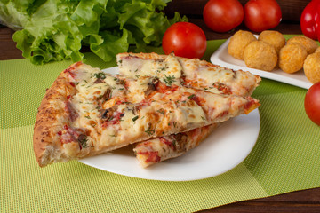 Pizza assorted slices with nuggets on a green napkin. Still-life. Wooden table. Greens and vegetables.