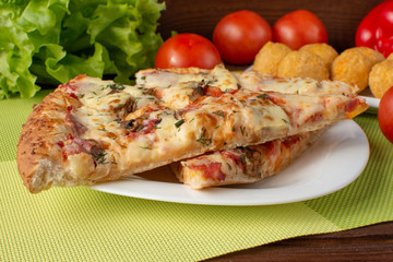 Pizza assorted slices with nuggets on a green napkin. Still-life. Wooden table. Greens and vegetables.