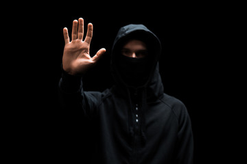 selective focus of anonymous hacker in hood with outstretched hand isolated on black