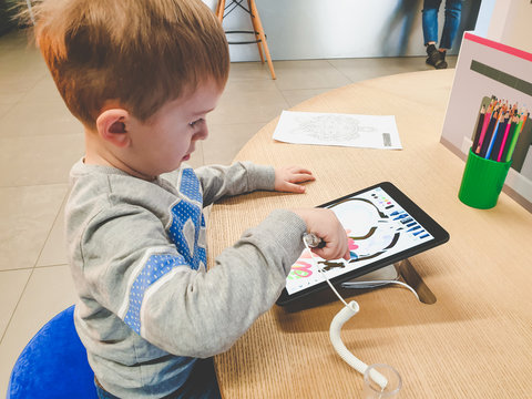 Toned Image Of Child Using Tablet Computer For Drawing In Kindergarten Or Primary School