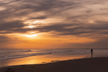 Fototapeta na wymiar Man in silhouette on sandy beach at sunset