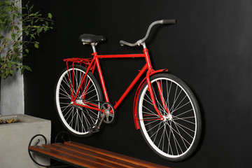 Fototapeta na wymiar Red bicycle hanging on black wall indoors