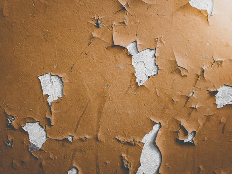 Closeup toned photo of old brown painted wall with cracks and oil pieces peeling off