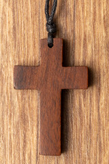 Wooden cross on wooden background top view copy space