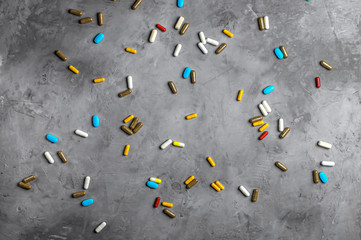 multicolored tablets and capsules on a grey concrete background