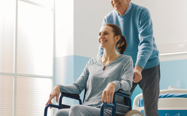 Father assisting her daughter in wheelchair