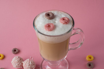 Cappuccino in a glass with bright colorful candies. still-life. coffee.
