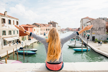 Fototapeta na wymiar Young woman enjoying the view of the canal in Murano, Venice in Italy