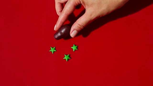 top view on woman hand puts ingredients to make marzipan eggplant shaped candy