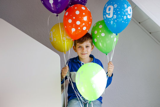 Portrait of happy kid boy with bunch on colorful air balloons on his birthday. Smiling school child having fun, celebrating nineth birth day. Family and best friend party