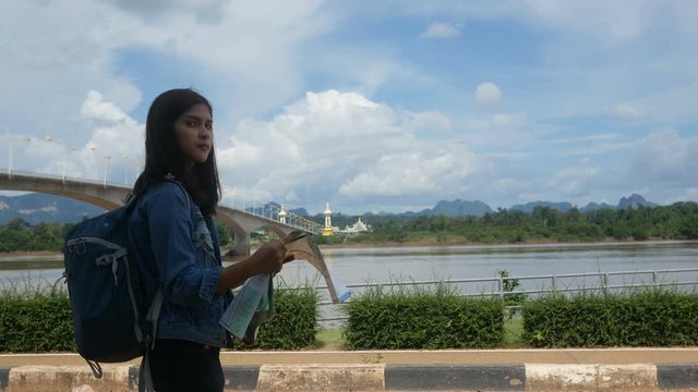 A portrait of a young asian woman travel backpacking in Nakhon phanom , Thaiand, outdoor looking at map