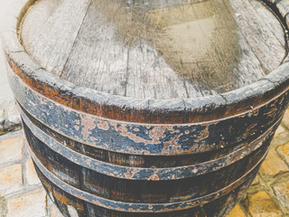 Fototapeta premium Closeup toned image of old wooden barrel with metal rings on the street