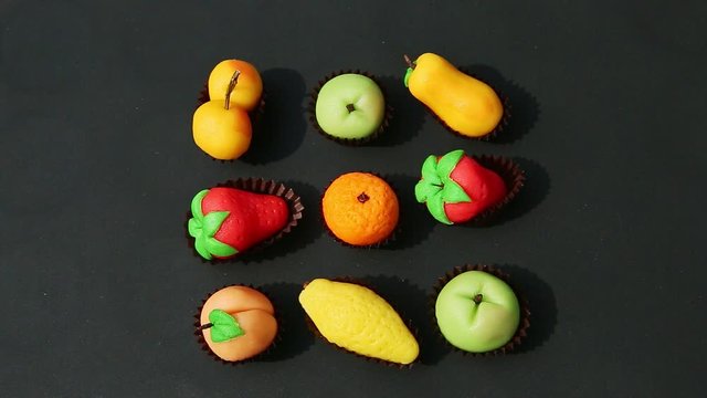 top view on hand takes away fruit shaped marzipan candy from assortment