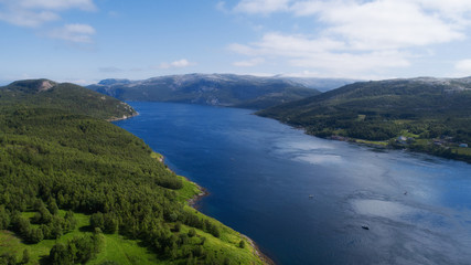Aerial view of mountains and fjord in Norway. Clouds and blue sky.