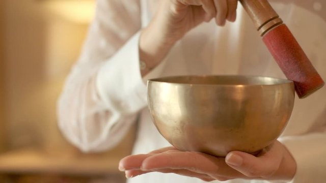 Young woman meditates doing yoga with Singing Bowl. Close-up.